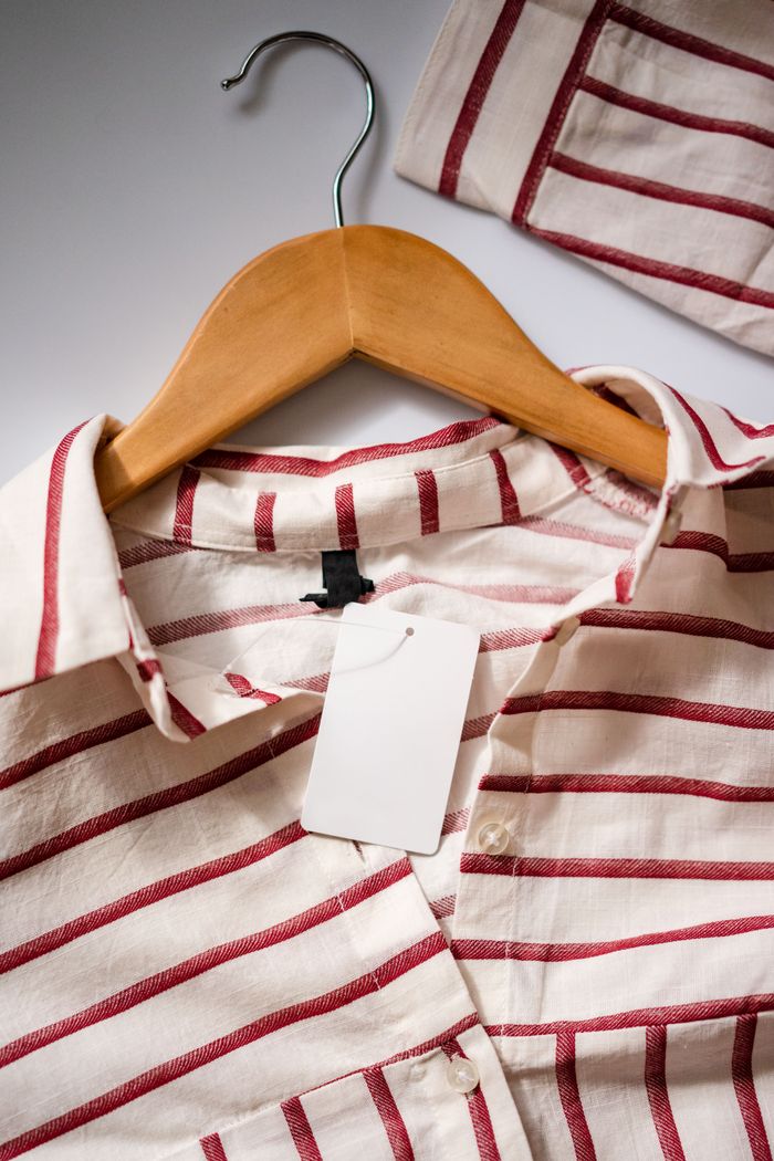 Close-up of a red and white striped shirt on a wooden hanger.