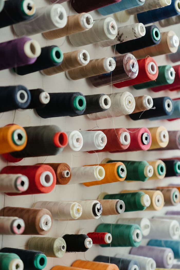 A collection of assorted spools of thread neatly organized by color on a wall rack.