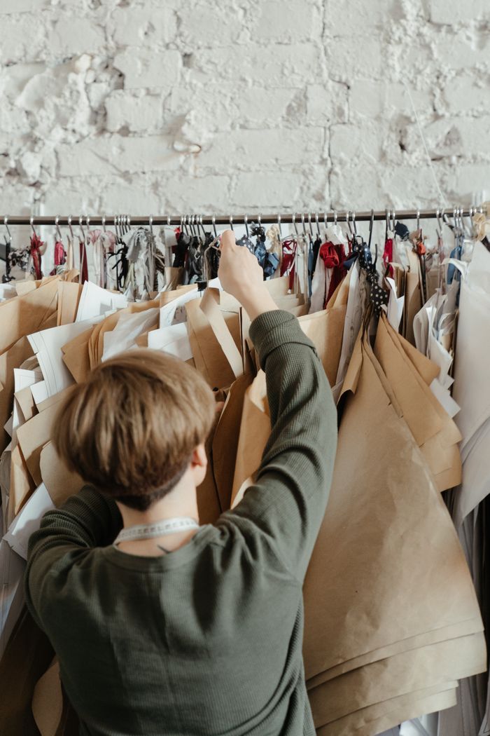 Fashion designer organizing paper patterns in a creative studio environment.